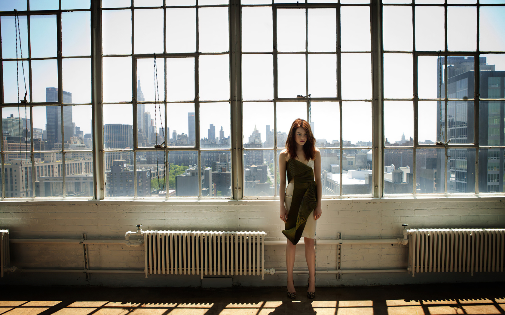 Популярная актриса Эмма Стоун стоит у большого окна