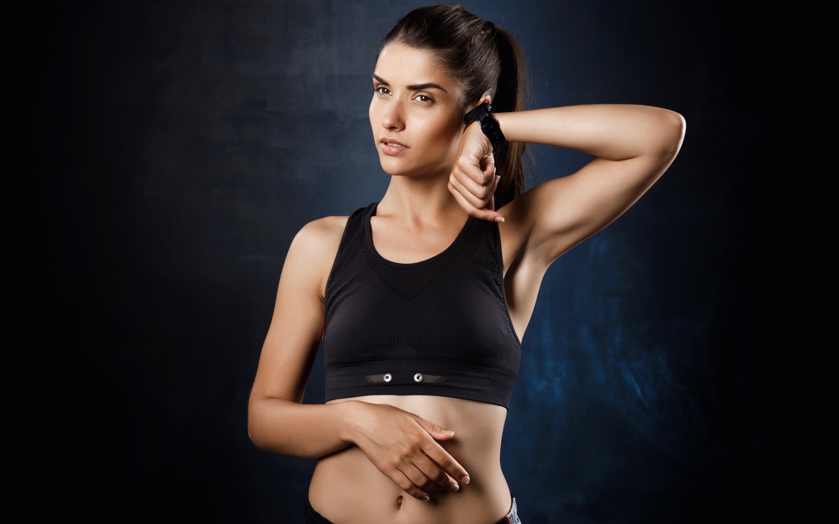 Спортивная девушка в черном костюме с часами на руке