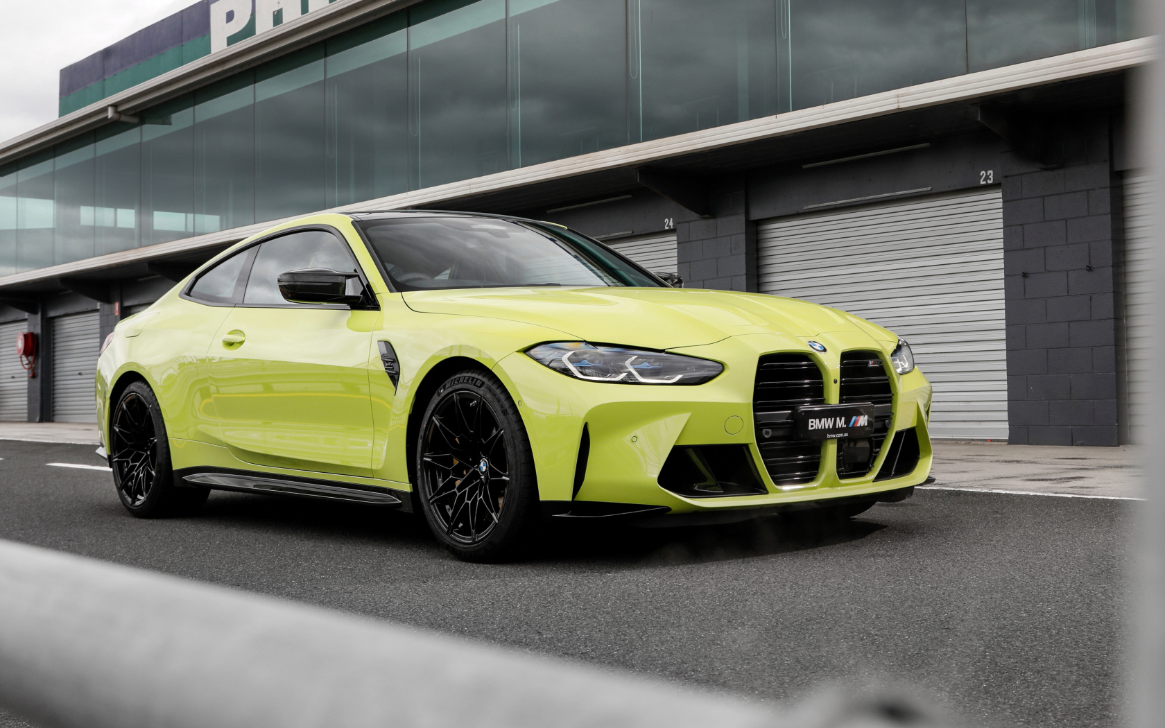 Желтый автомобиль BMW M4 Competition 2021 года у здания