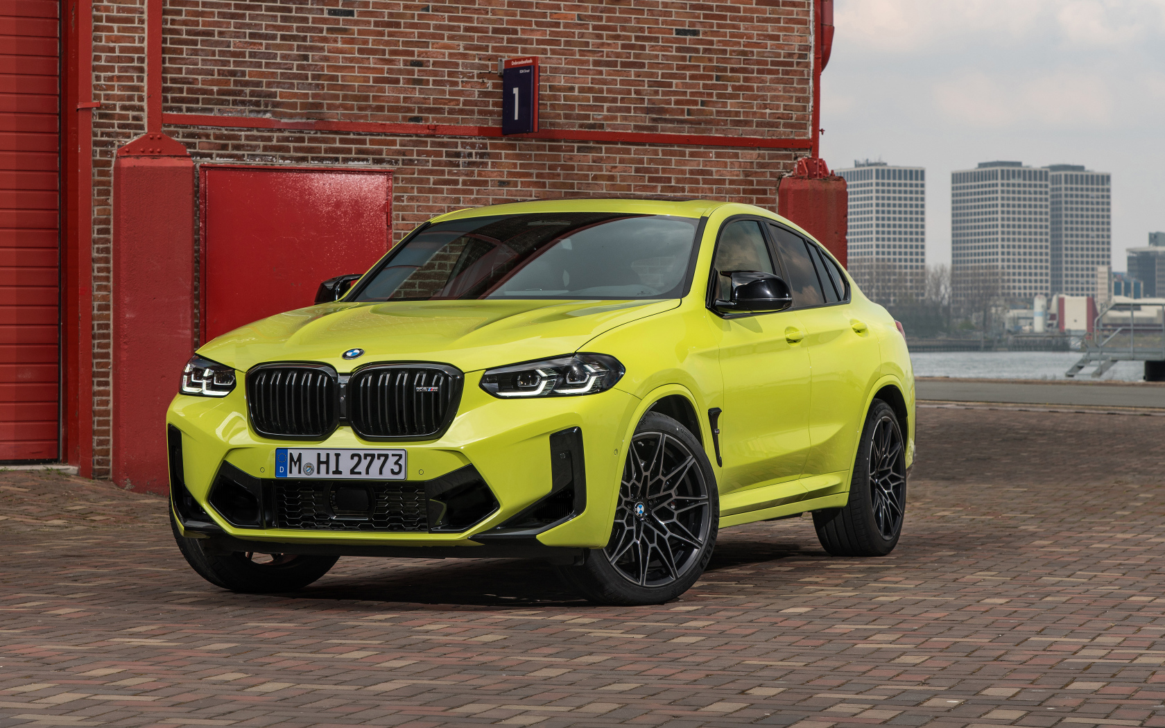 Желтый автомобиль BMW X4 M Competition 2021 года у стены