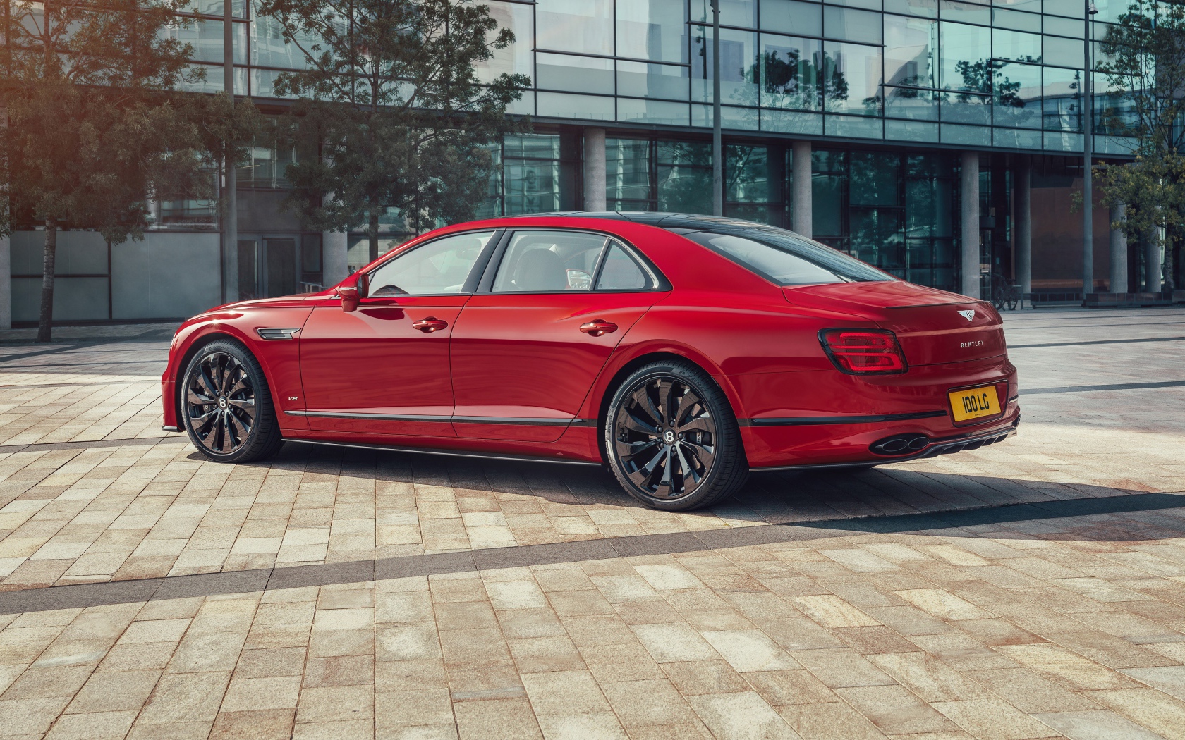 Красный автомобиль Bentley Flying Spur V8 2020 года у здания 
