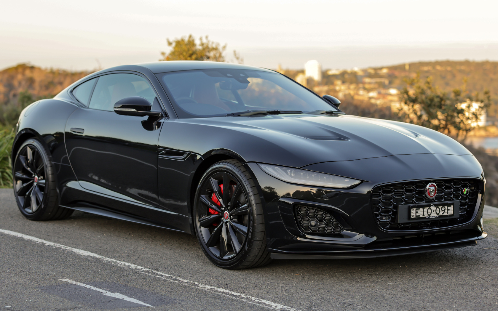 Дорогой черный автомобиль Jaguar F-Type R на дороге