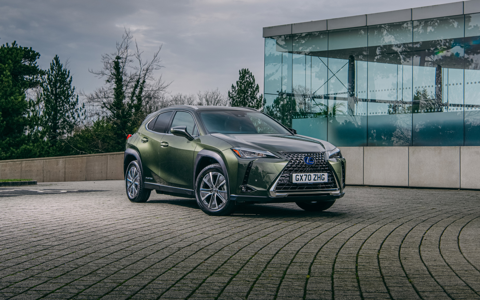 Зеленый автомобиль Lexus UX 300e 2021 года у стеклянной стены