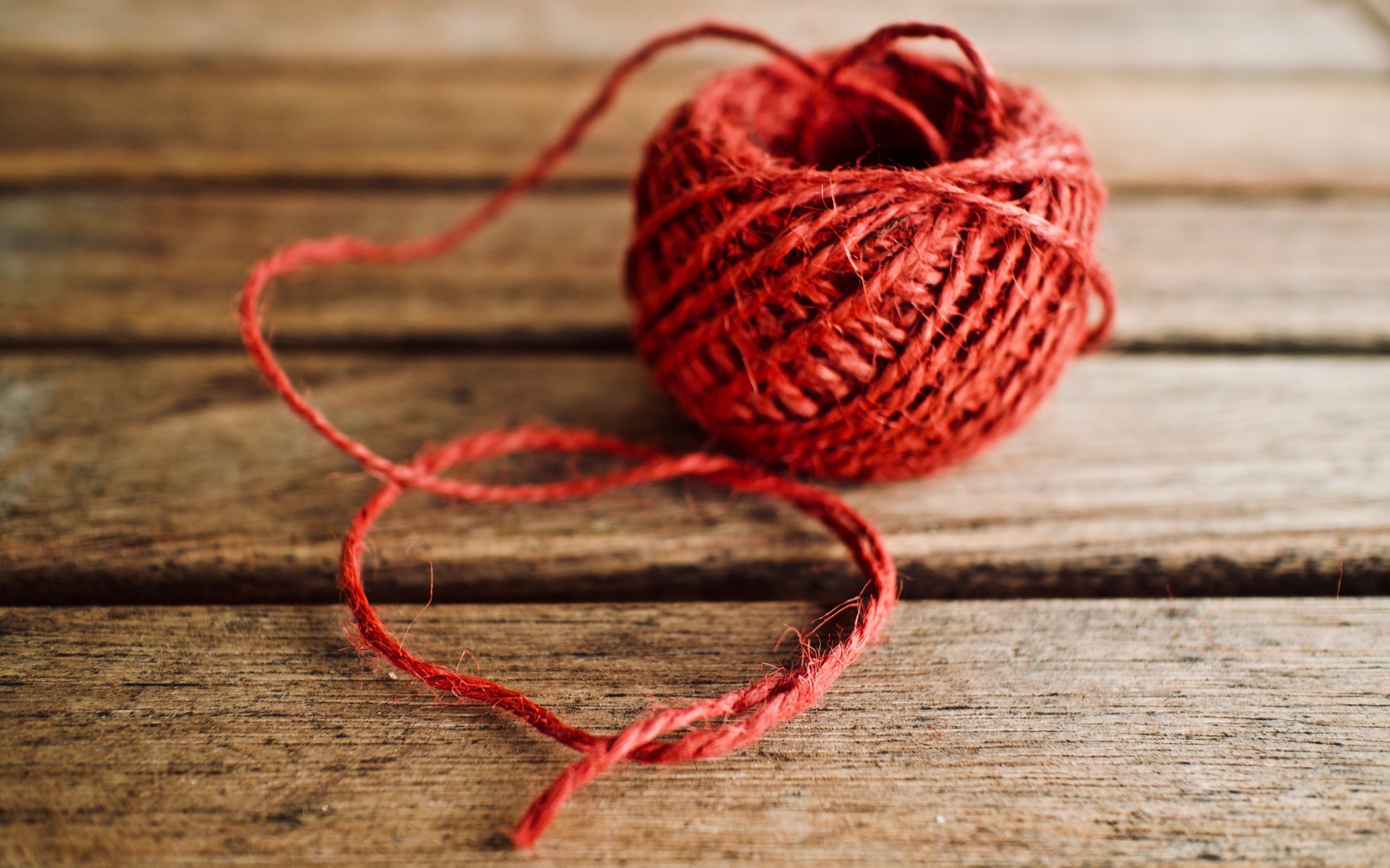 Клубок красной пряжи на деревянном столе 