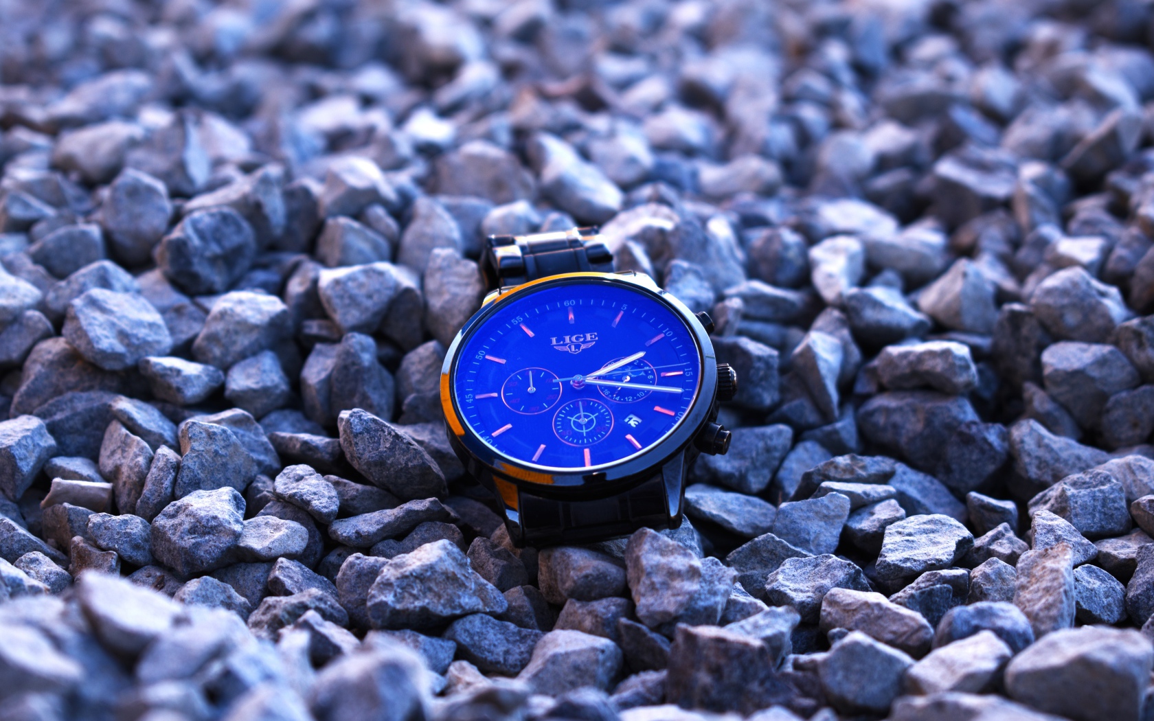 Голубые наручные часы лежат на камнях