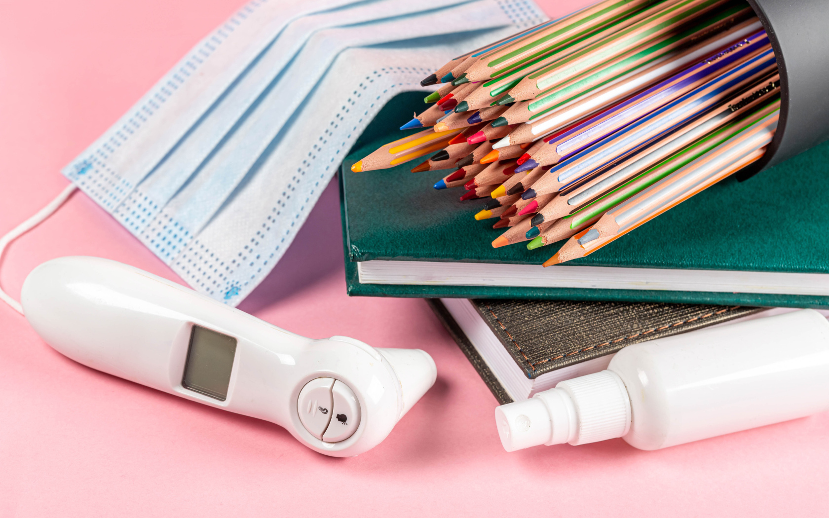 Карандаши, градусник, маска и блокнот на розовом фоне 