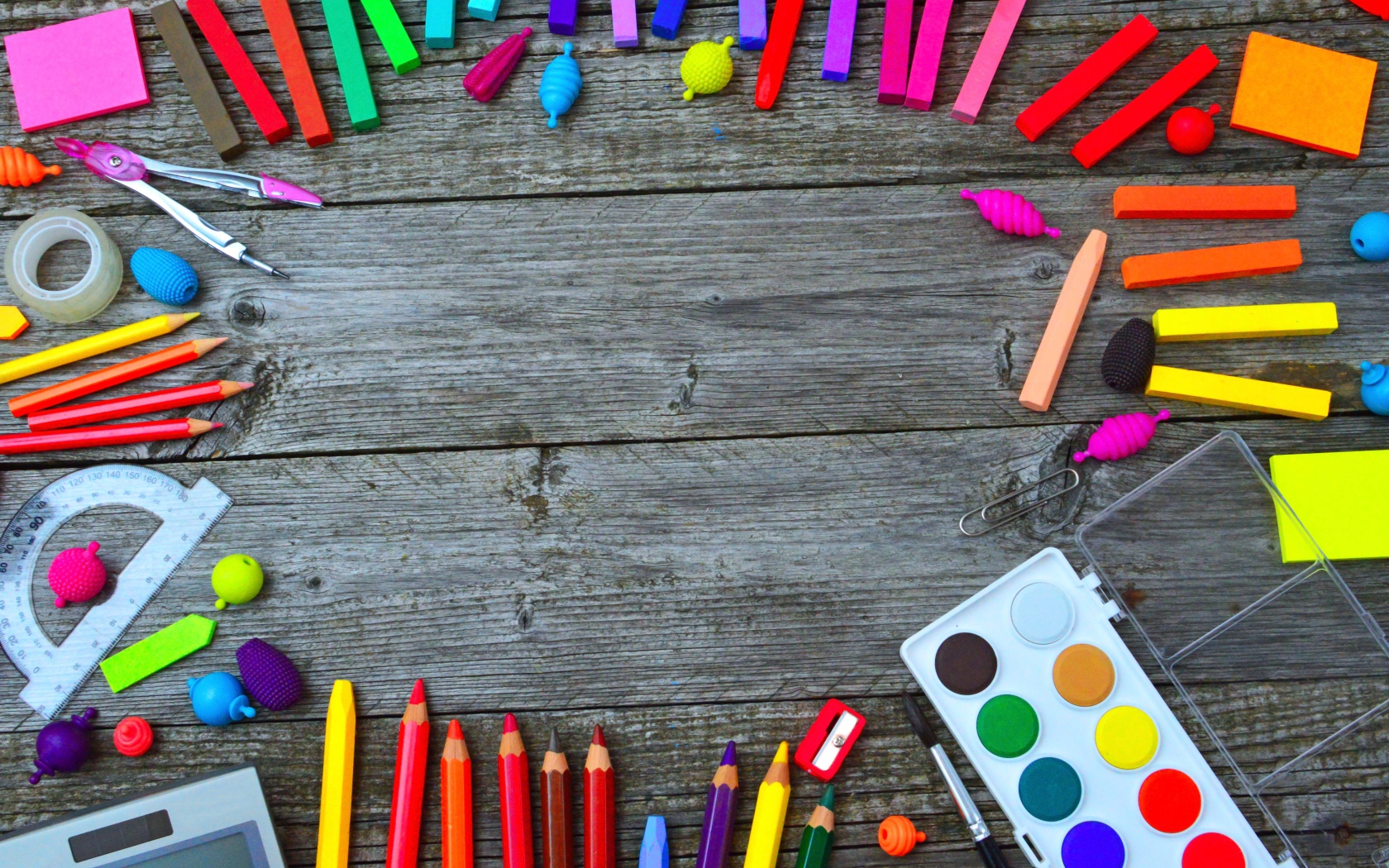 Радуга ярких канцелярских предметов для школы  на деревянном столе