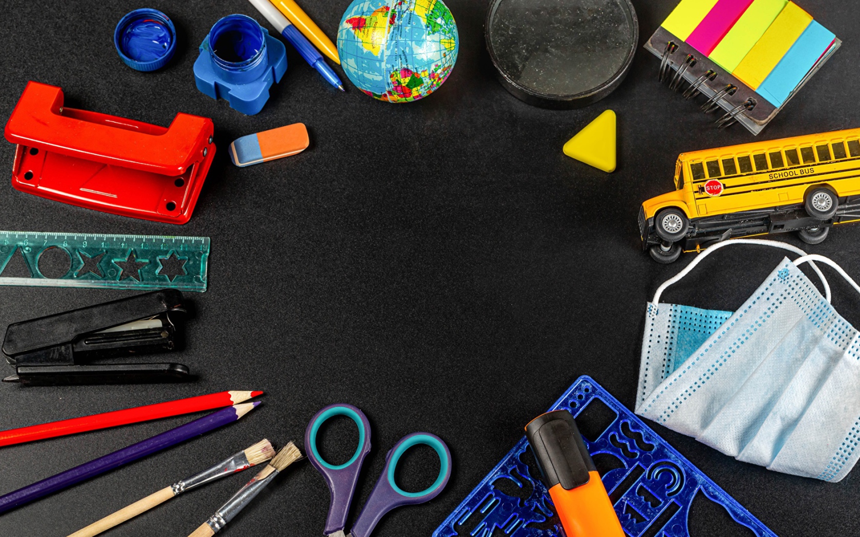 Канцелярские предметы, игрушки и маска на черном столе 