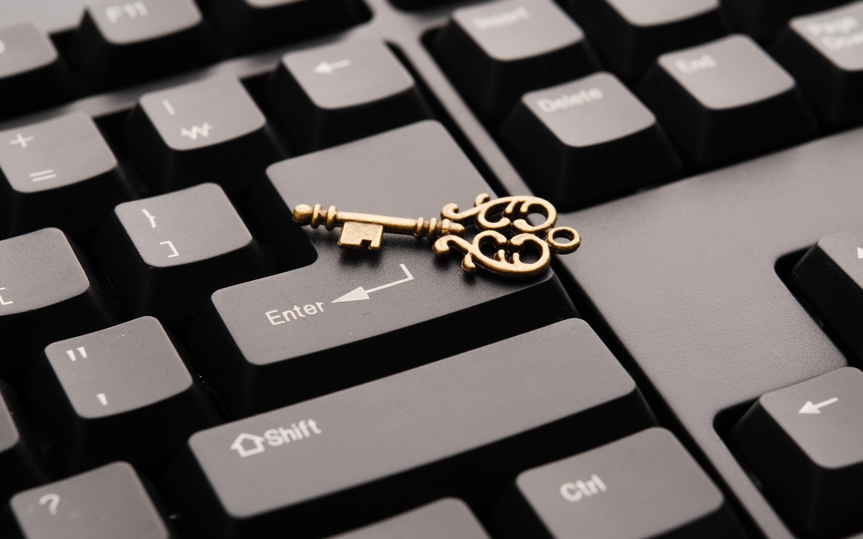 Золотой ключ лежит на черной клавиатуре
