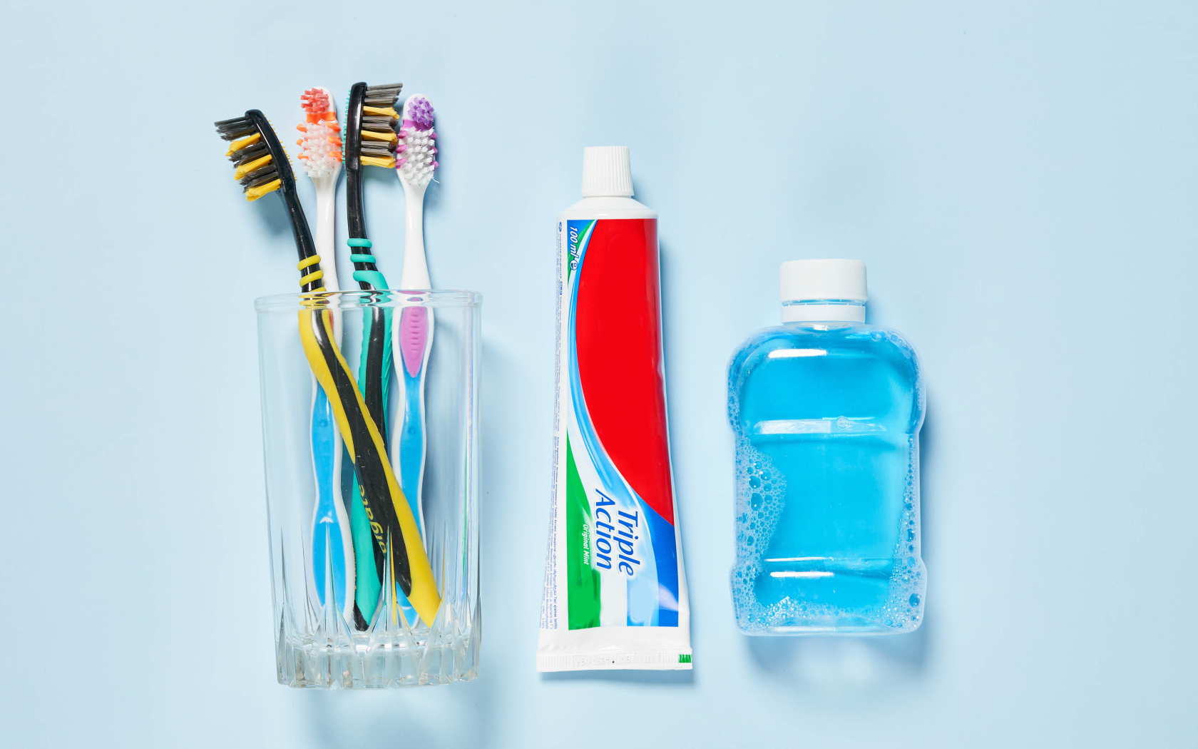 Зубная паста с щетками и ополаскивателем на сером фоне 