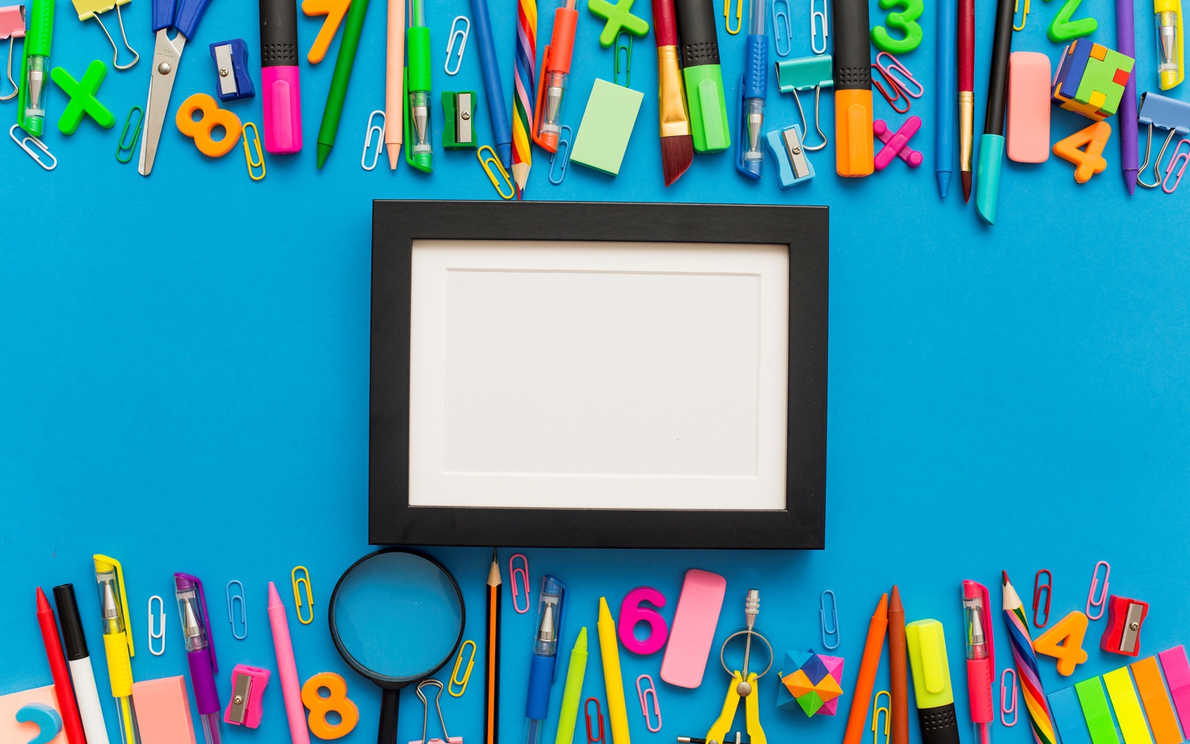Белая рамка с разноцветными канцелярскими предметами на голубом фоне