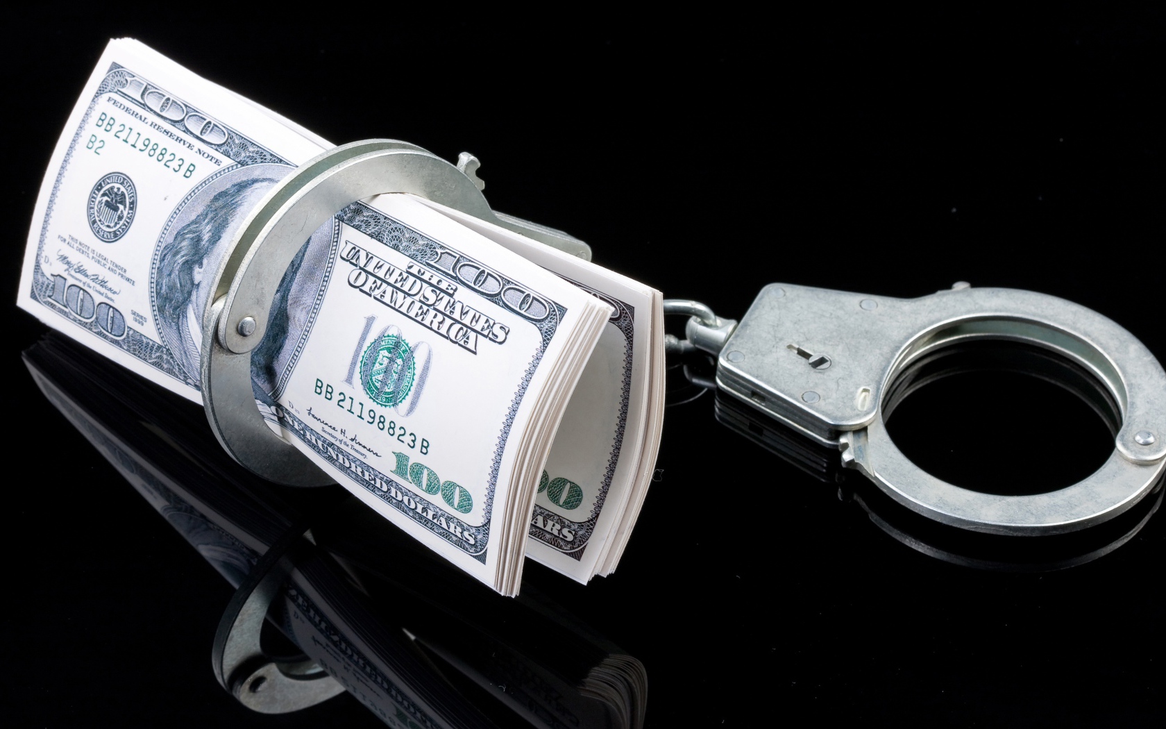 Пачка долларов с наручниками на черном фоне