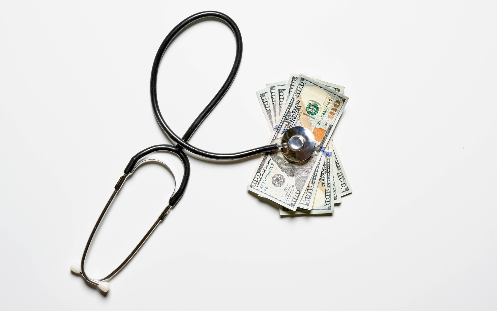 Фонендоскоп с долларами на белом фоне