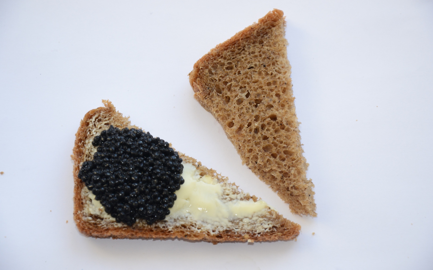 Бутерброды из черного хлеба с черной икрой на сером фоне