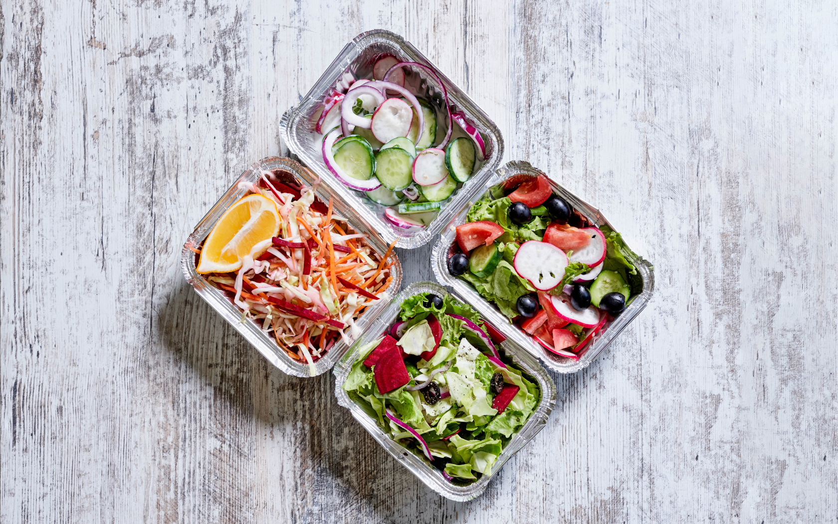 Разные овощные салаты в тарелках на сером столе 