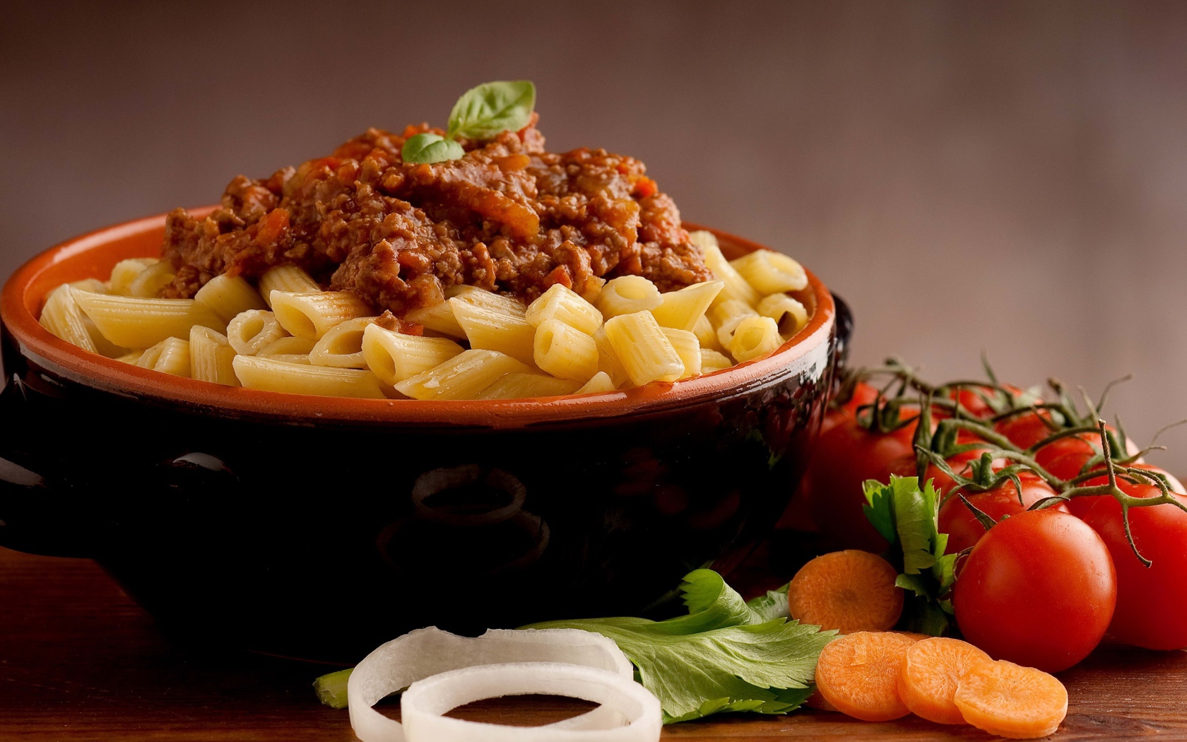 Макароны в миске с фаршем на столе с помидорами