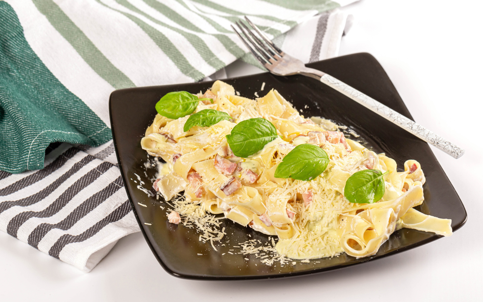 Макароны на тарелке с тертым сыром и кусочками мяса