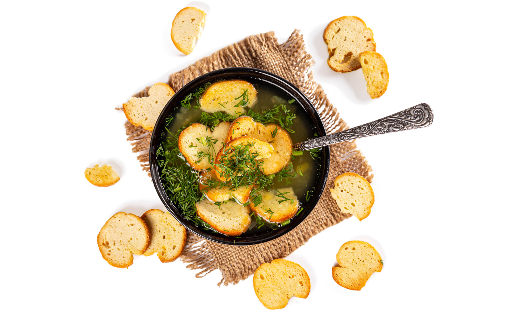 Суп с гренками и зеленью на столе на белом фоне