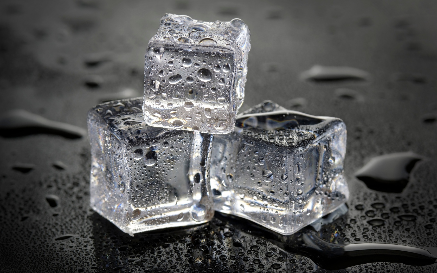 Три кусочка льда в брызгах воды на столе 