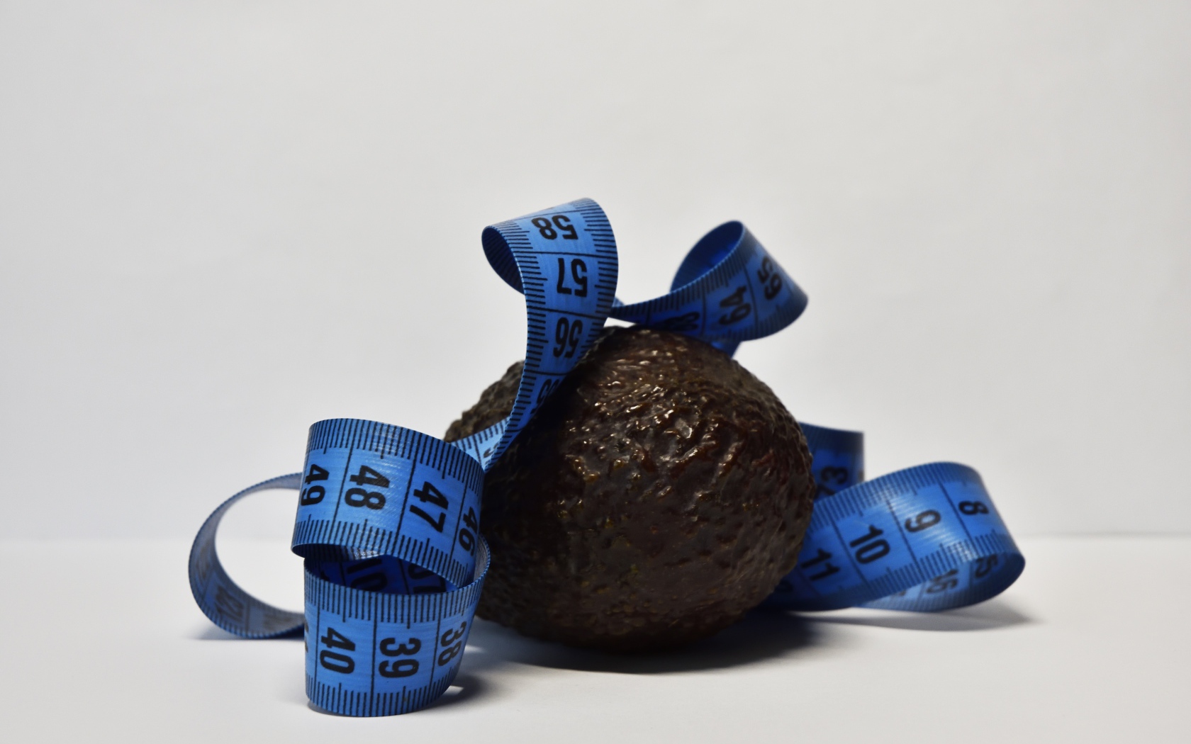 Авокадо с сантиметром на сером фоне