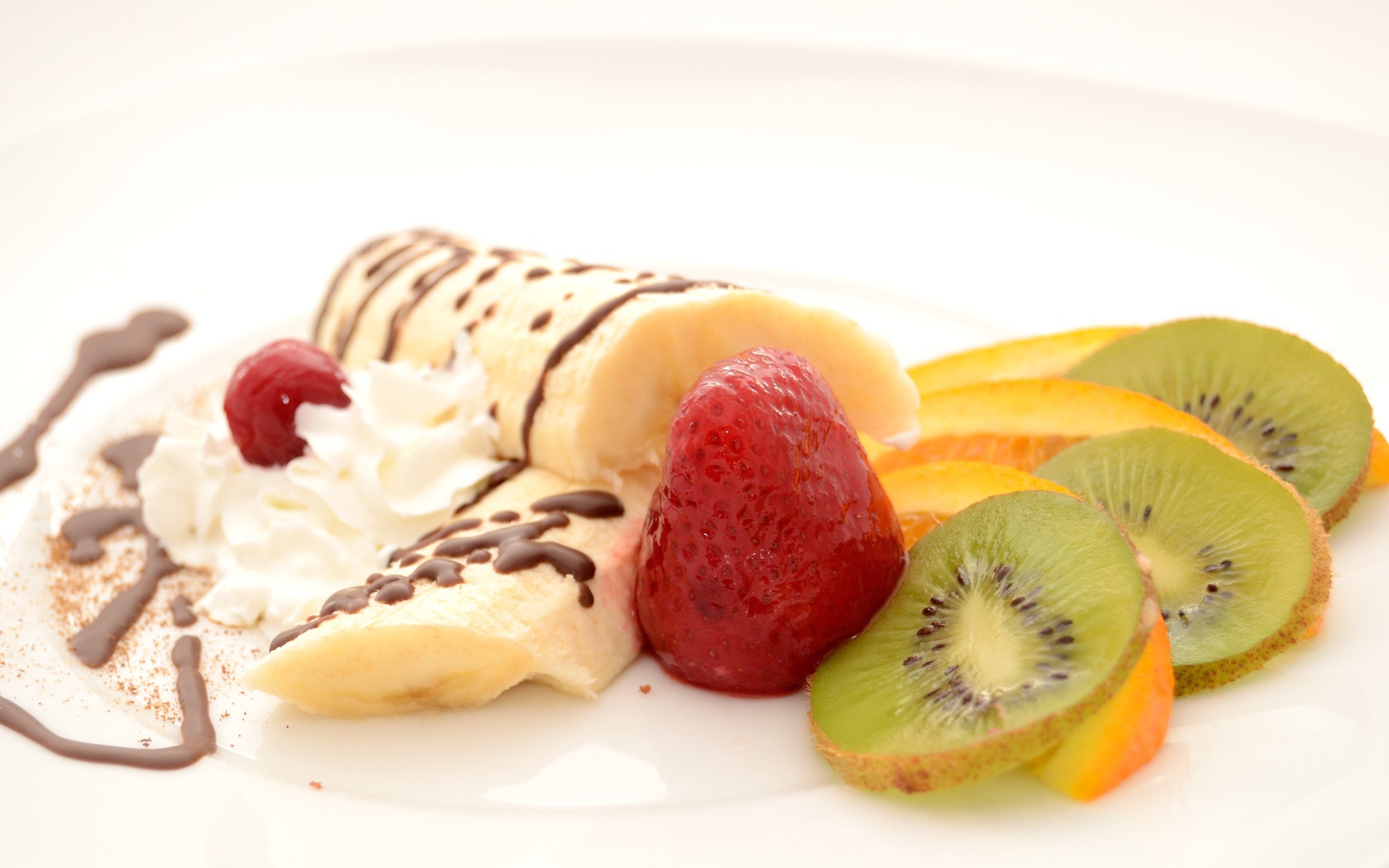 Бананы, киви и клубника на тарелке со сливками