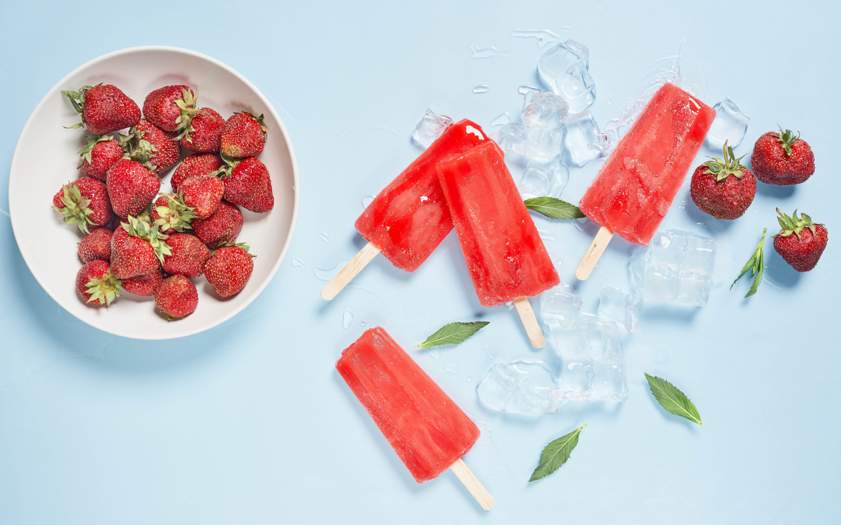 Мороженое со льдом и ягодами клубники на голубом фоне 