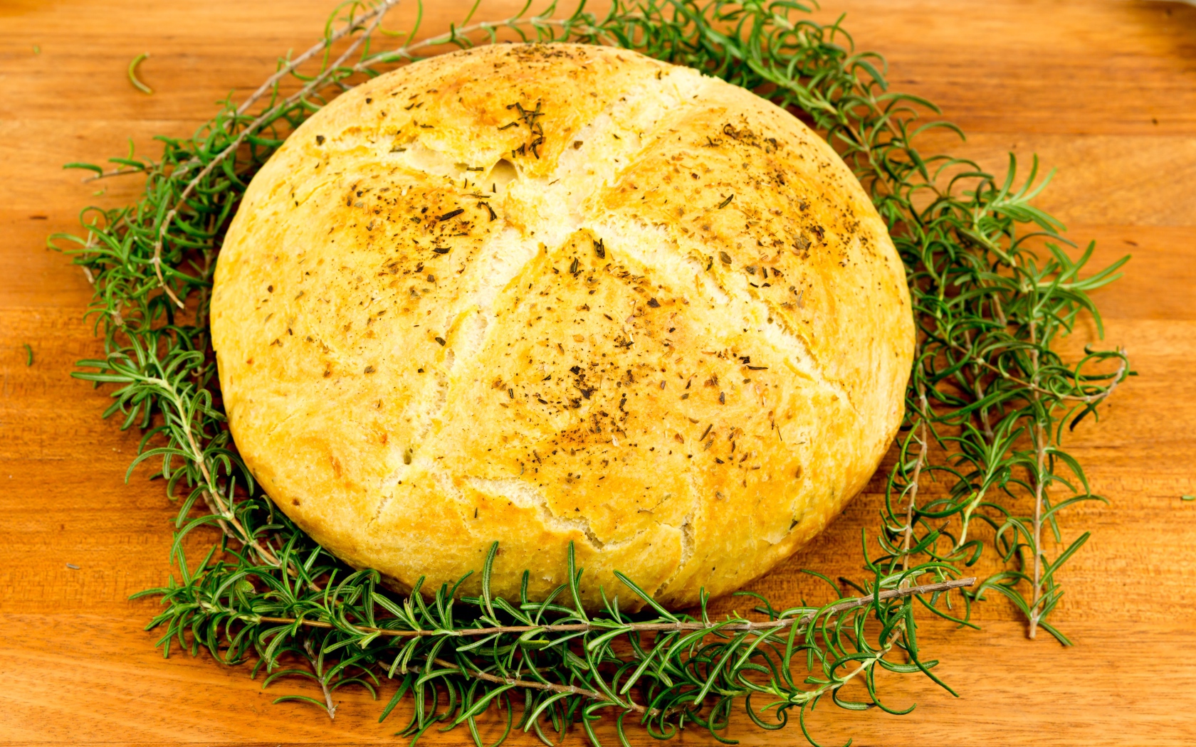 Буханка свежего ароматного хлеба с розмарином на столе