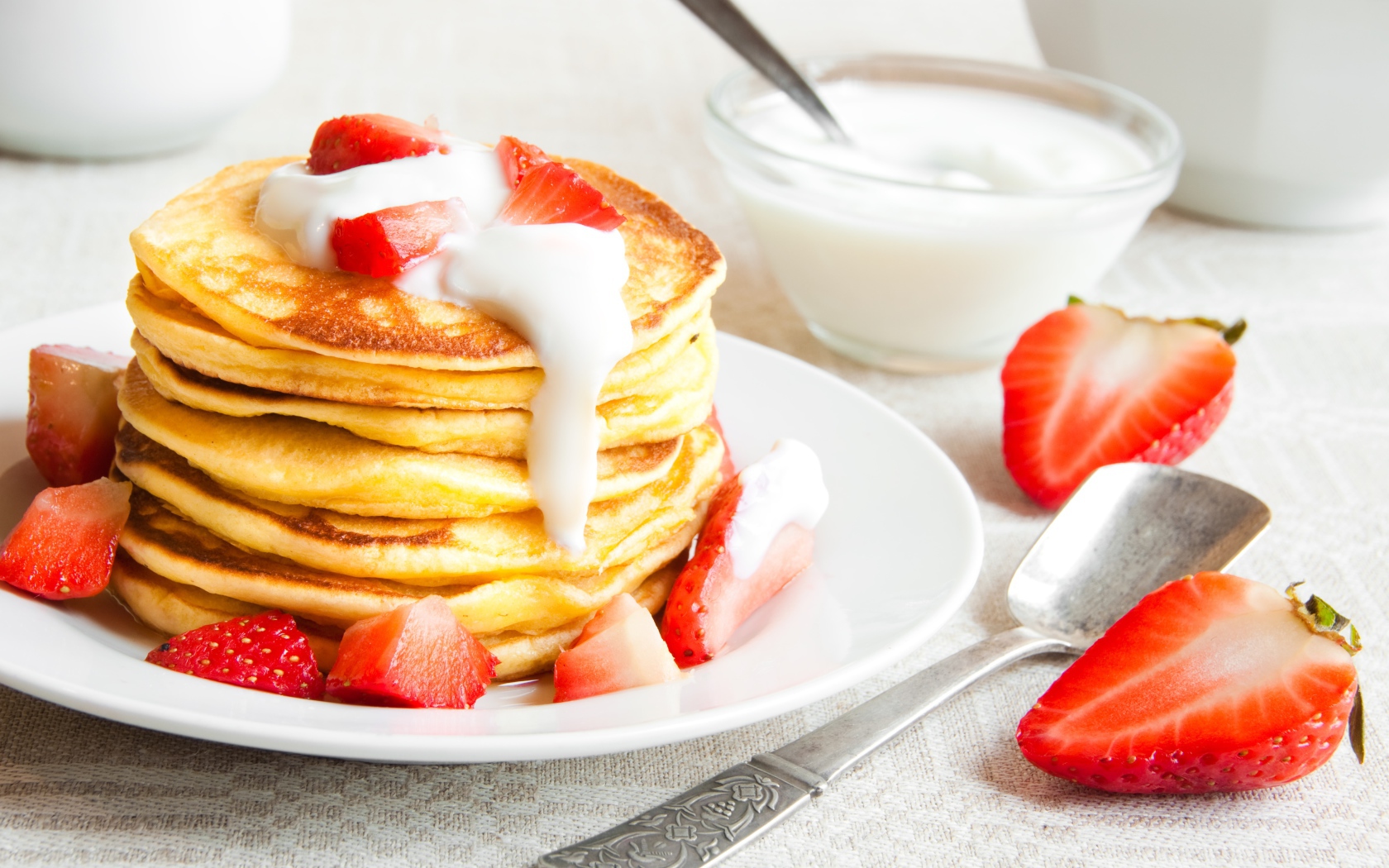 Оладьи с клубникой и сметаной на столе