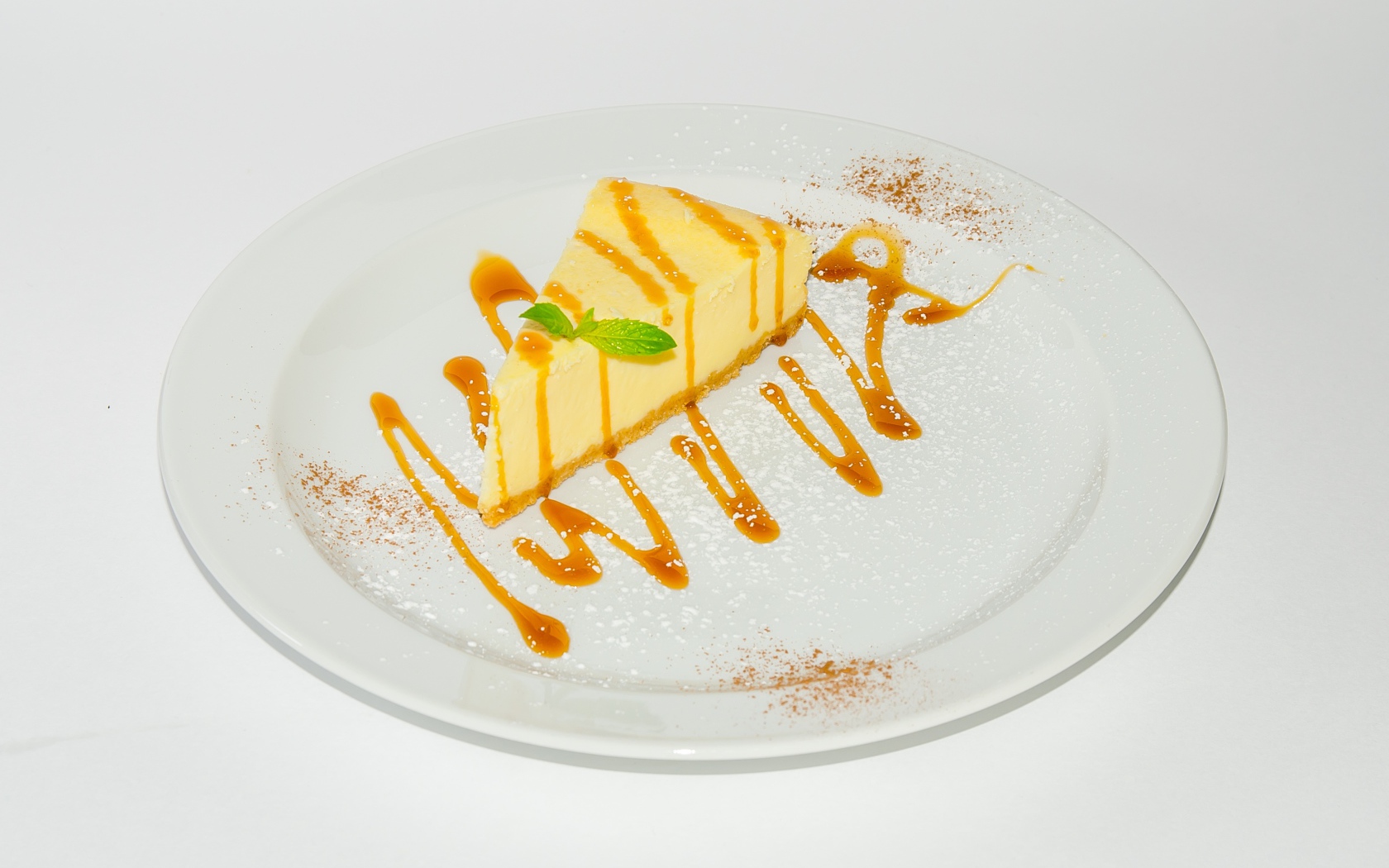 Кусок чизкейка с сиропом на большой белой тарелке 