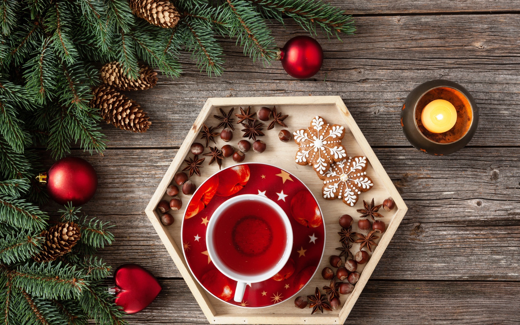 Чашка чая с печеньем и орехами на столе с еловой веткой