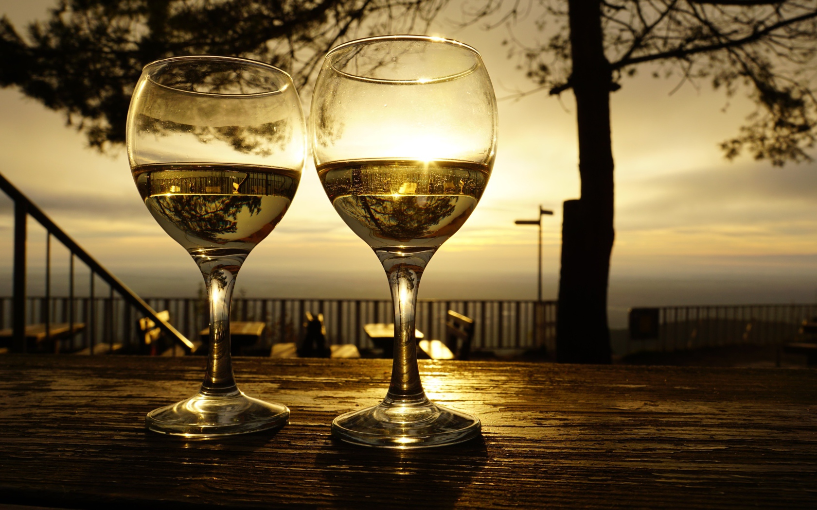 Два бокала белого вина на столе в лучах солнца