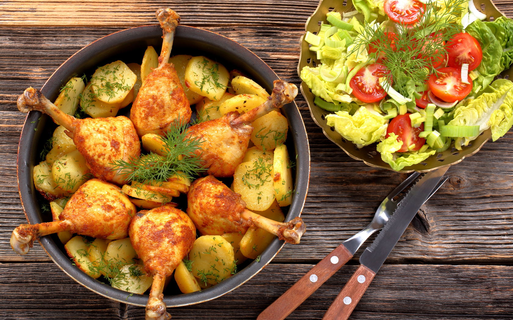 Fried chicken legs with potatoes on a table with salad