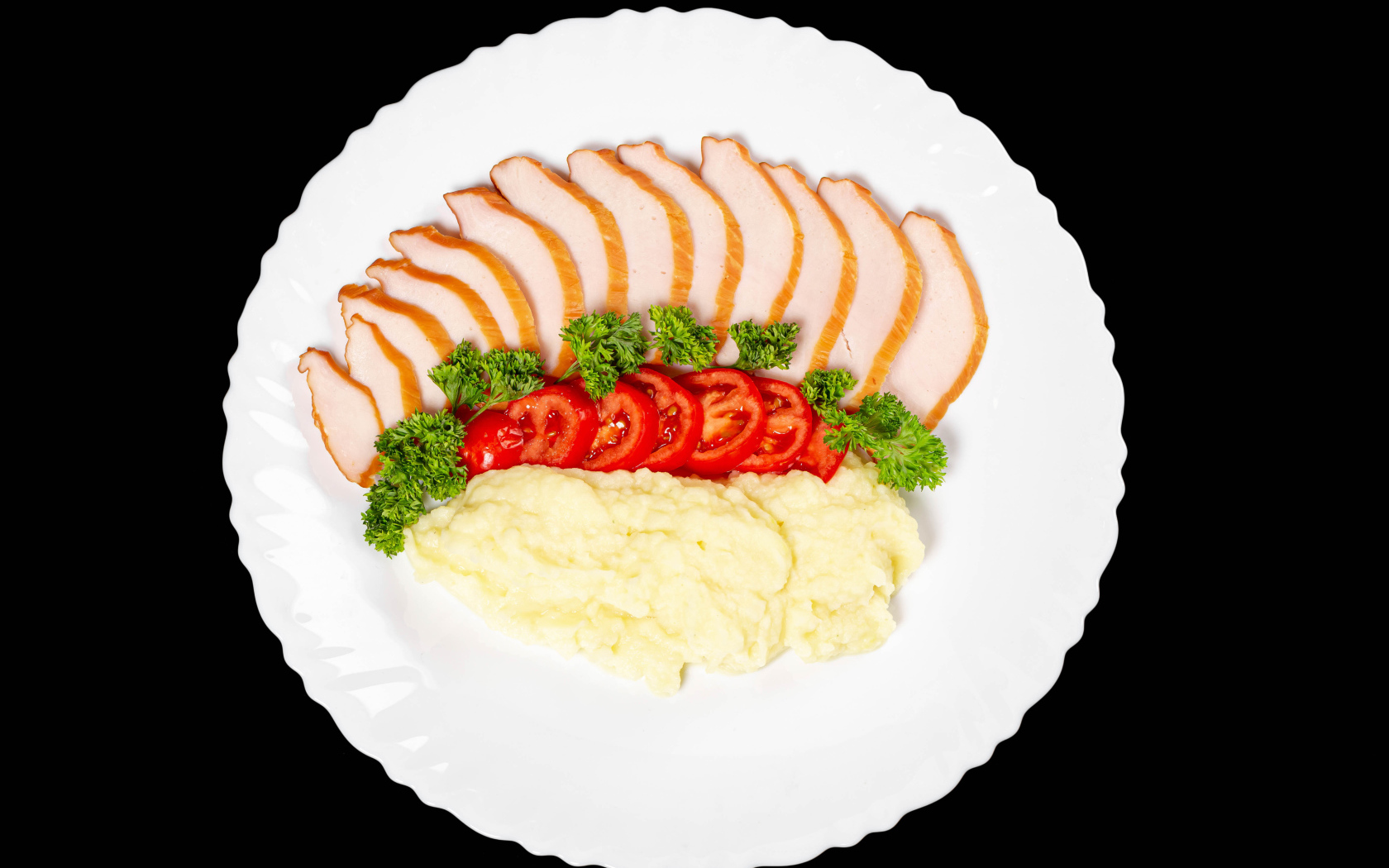 Ham on a large white plate with potatoes and tomatoes