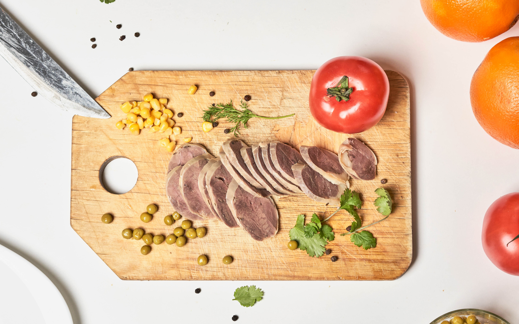 Sliced tongue with green peas on a board