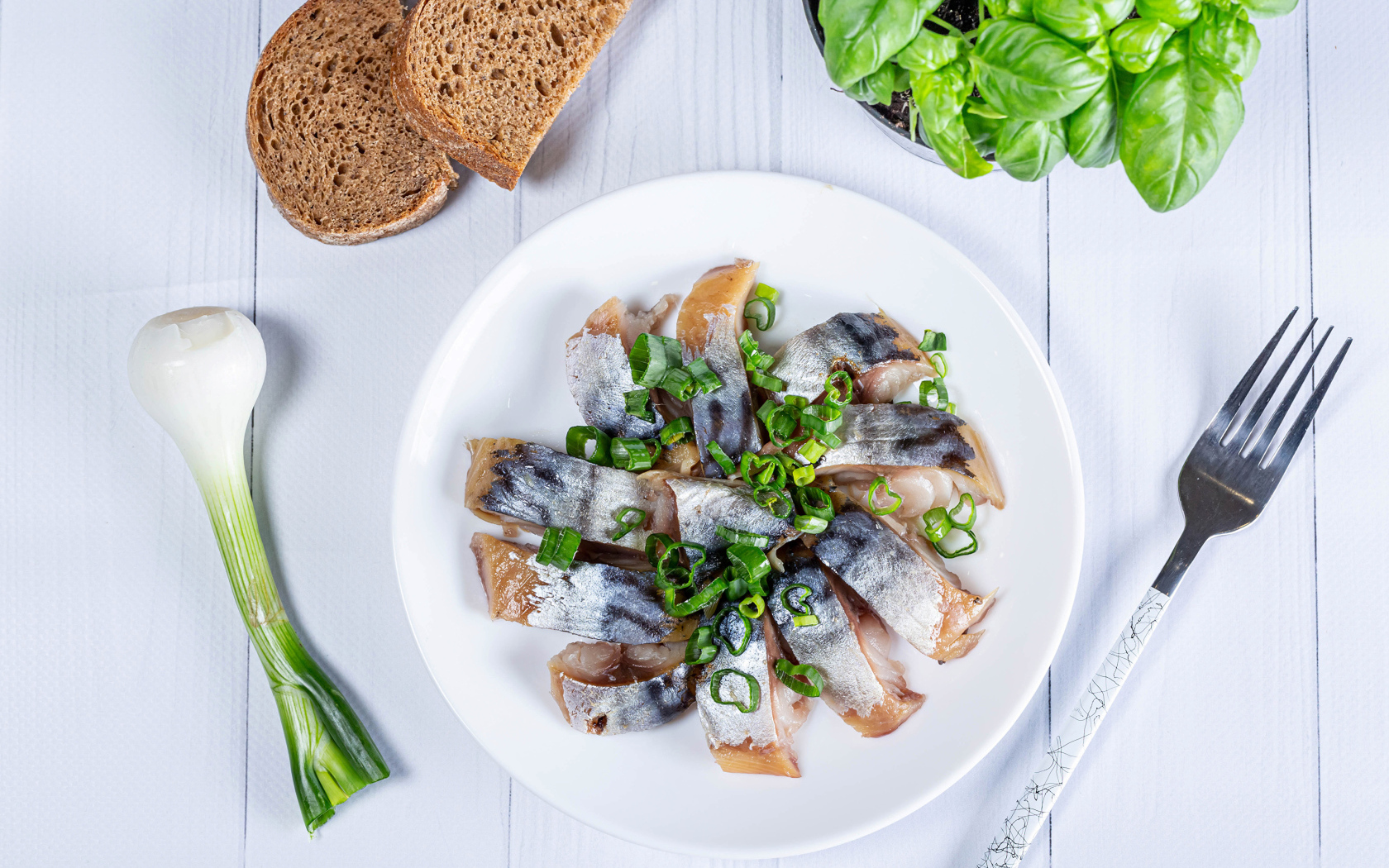 Куски скумбрии на столе с луком, хлебом и базиликом