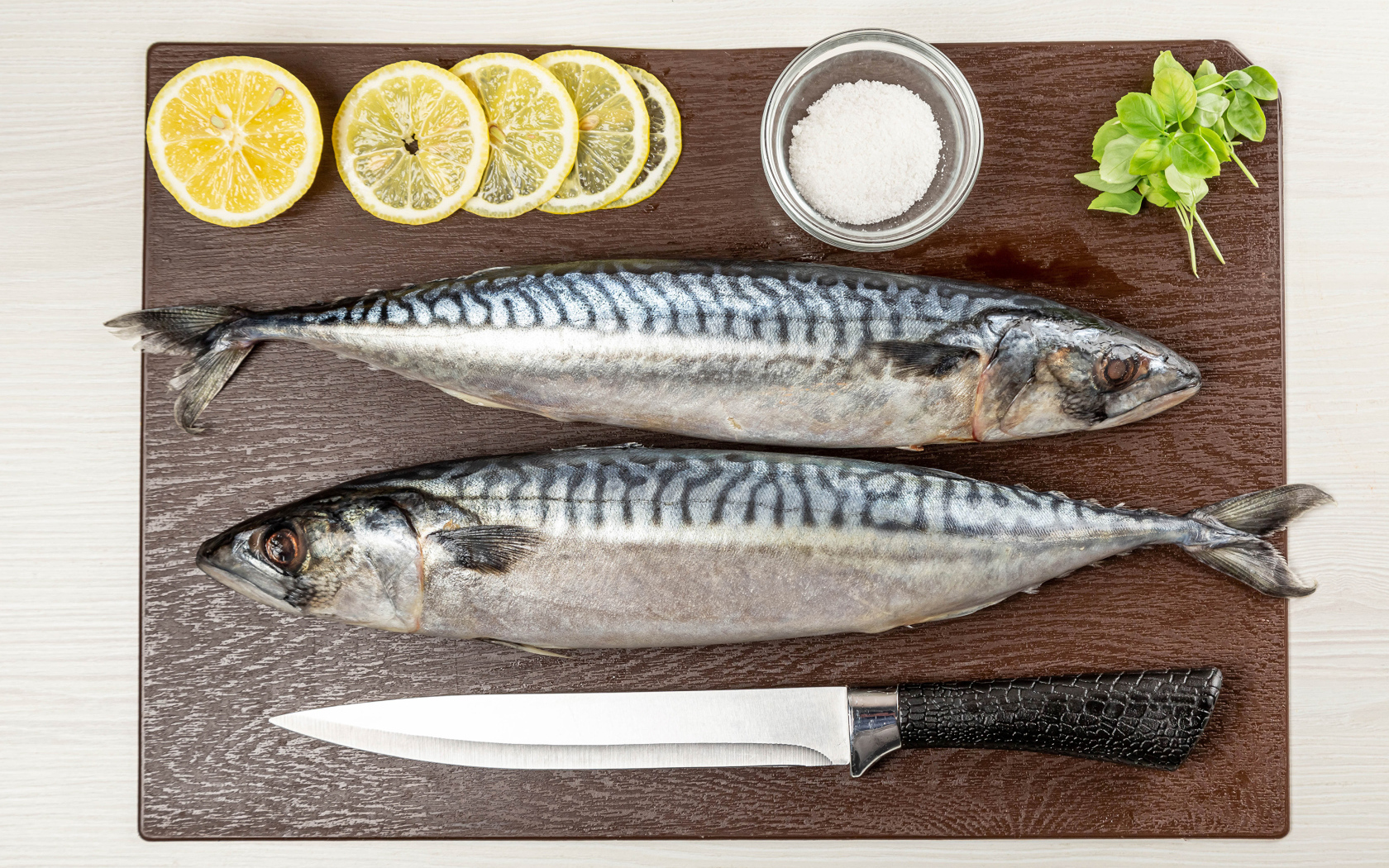 Two fresh mackerels on a board with lemon