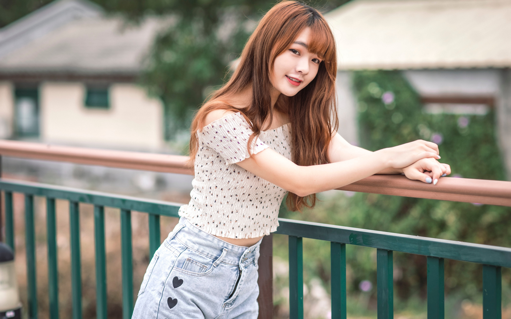 Красивая девушка азиатка стоит у перил у дома