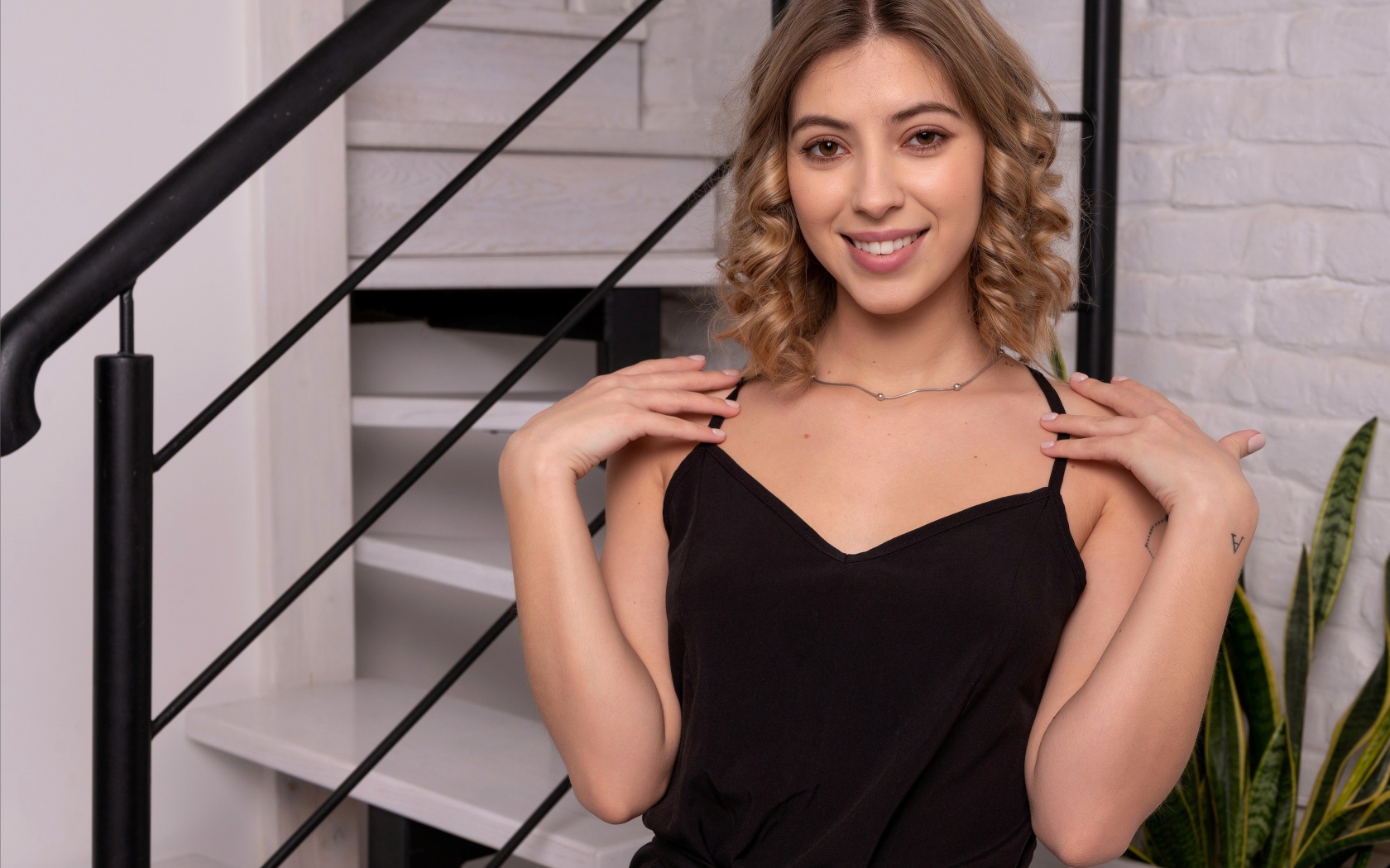 Девушка в черном платье стоит у ступеней