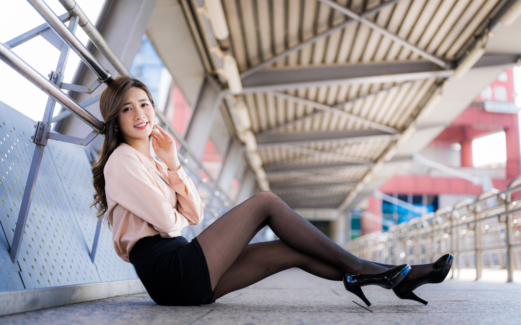 Девушка азиатка в черной юбке сидит в переходе 