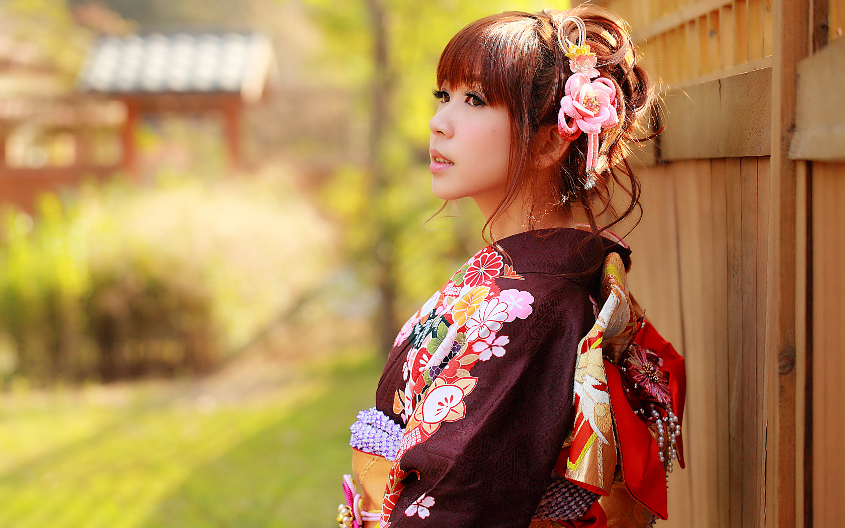 Asian girl in kimono stands at the fence