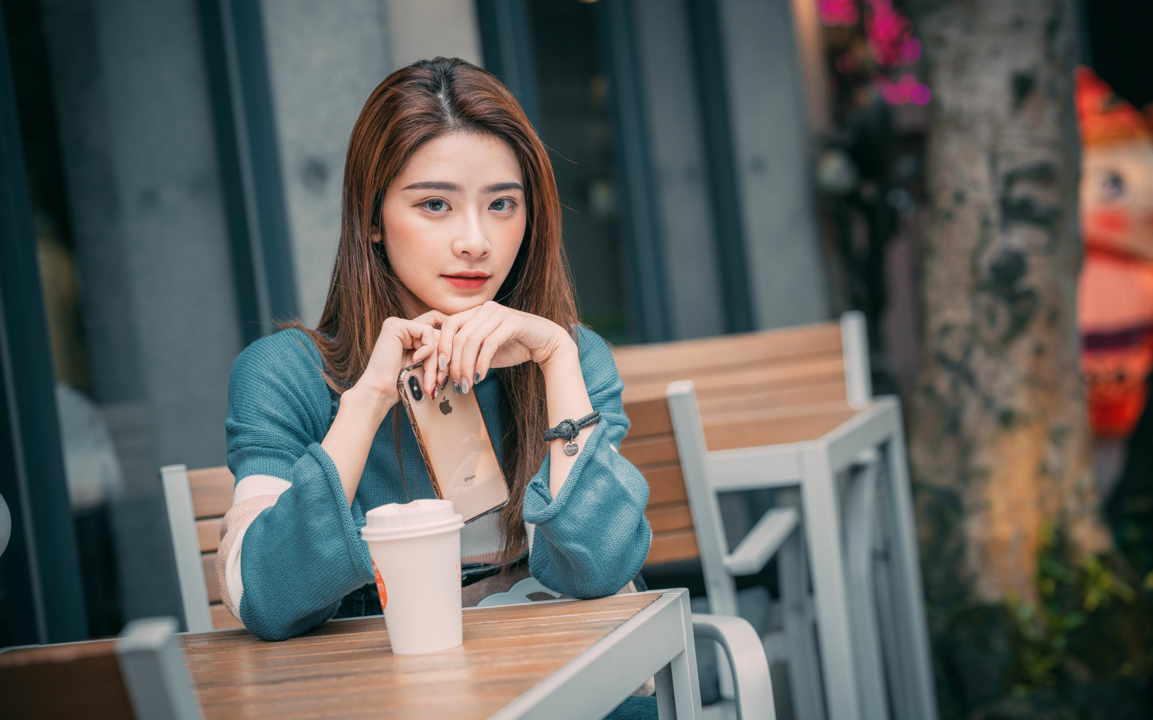 Девушка азиатка сидит за столом в кафе с телефоном 