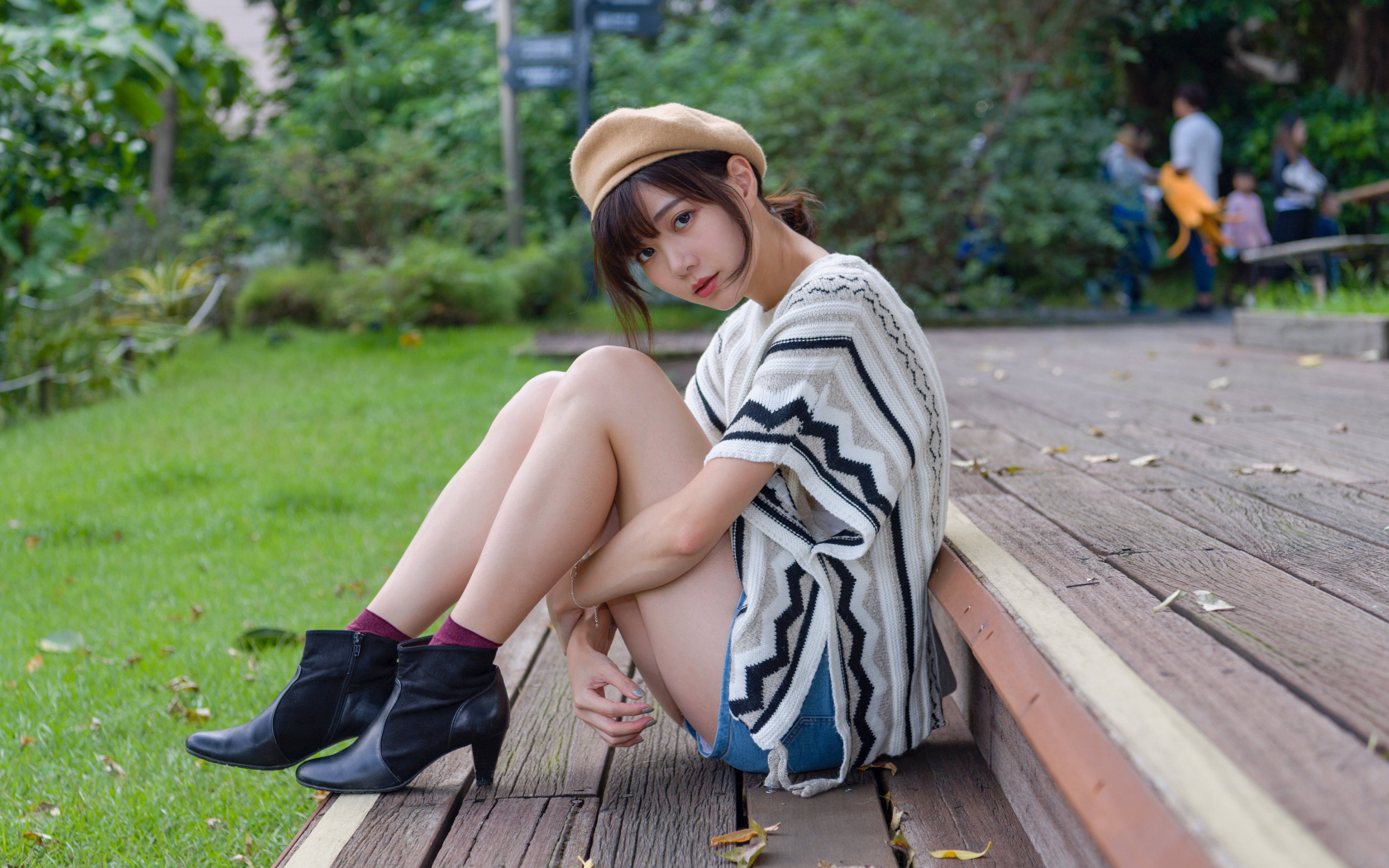 Девушка азиатка сидит в парке на лавке 