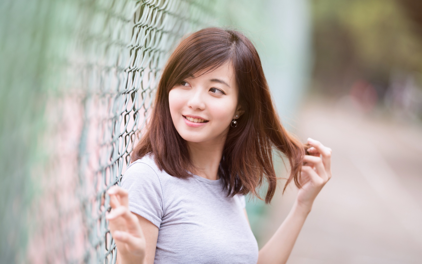 Девушка азиатка с милой улыбкой стоит у сетки 