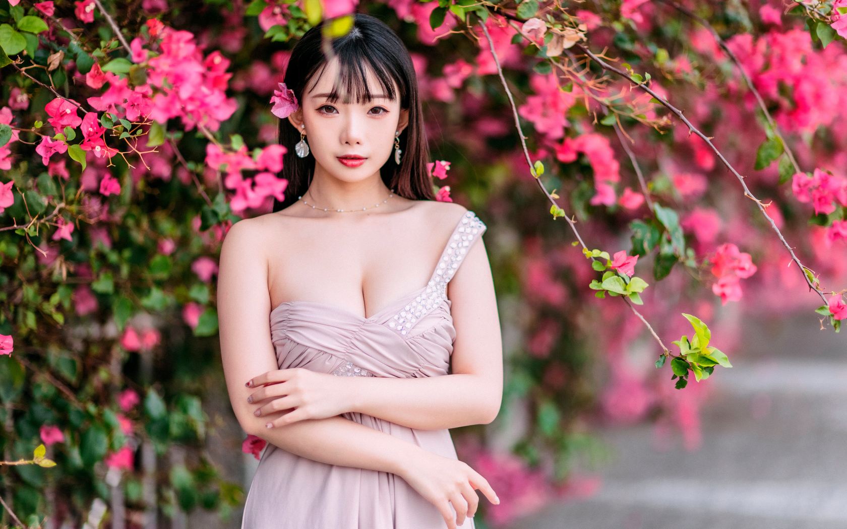 Красивая девушка азиатка у куста с  красными цветами 