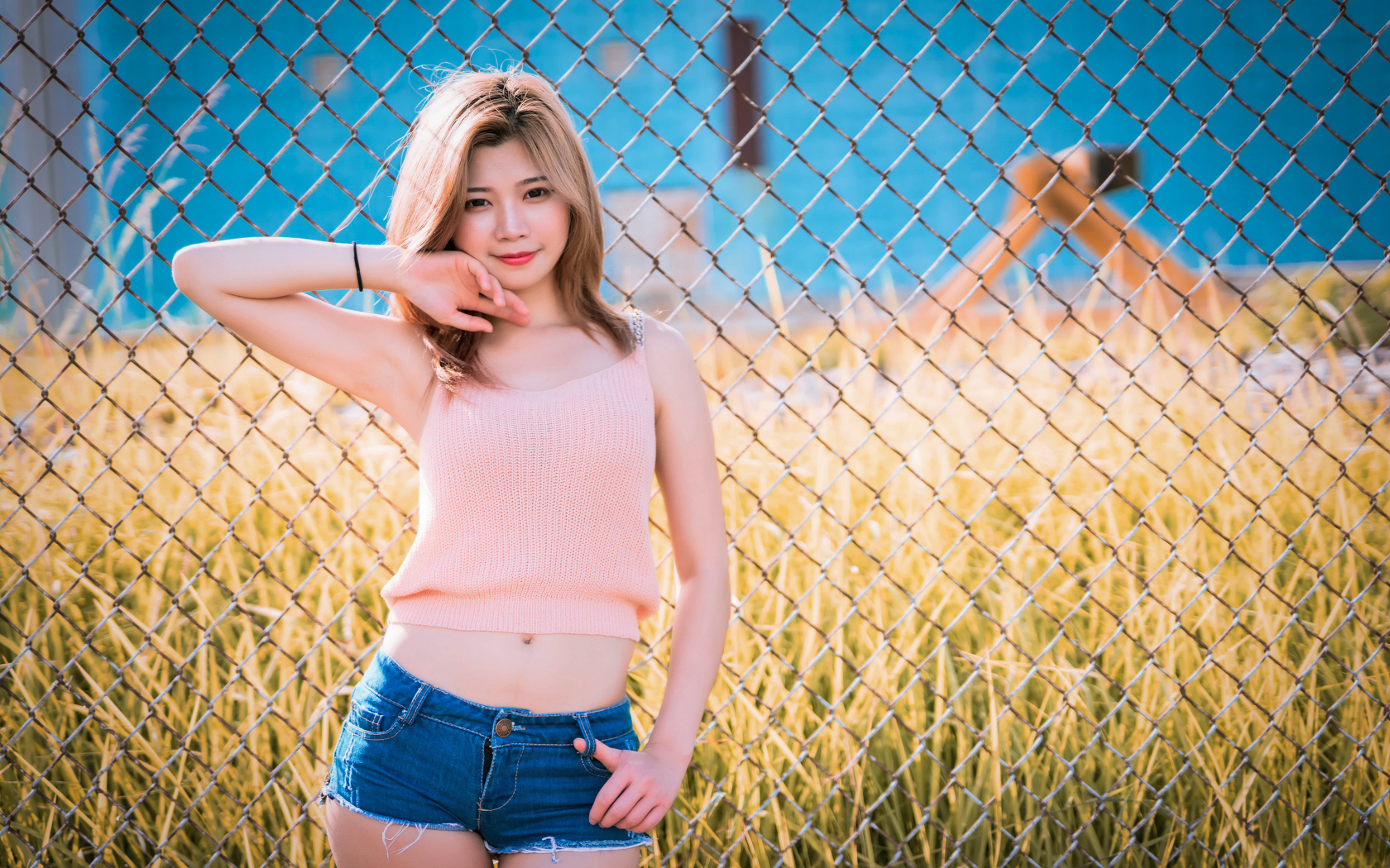 Красивая девушка азиатка стоит у железной сетки