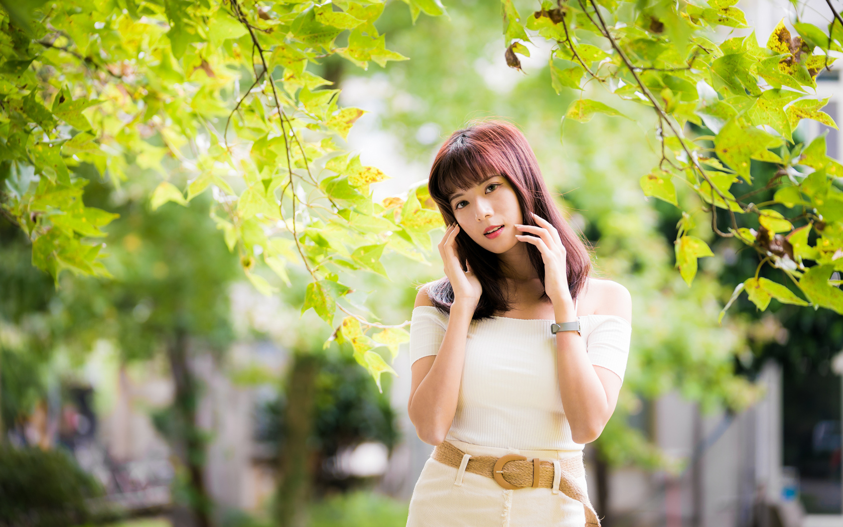 Красивая азиатка в белом платье у дерева 