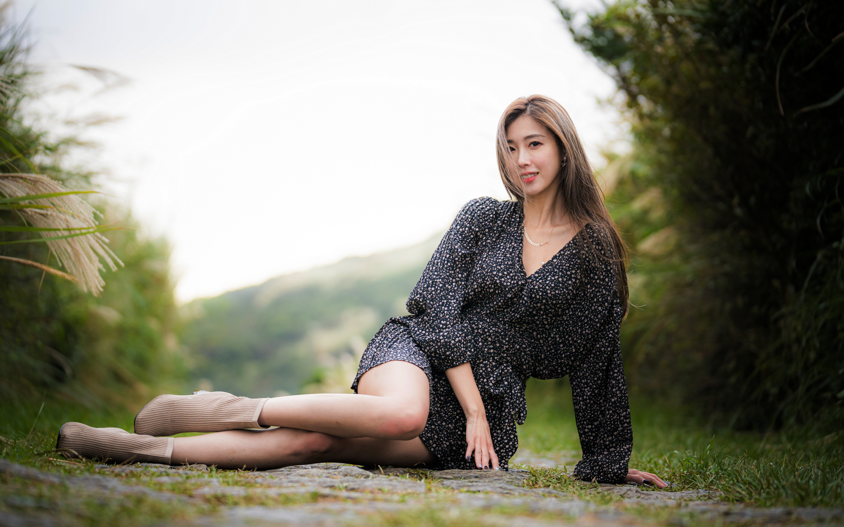 Красивая девушка азиатка в платье лежит на земле 