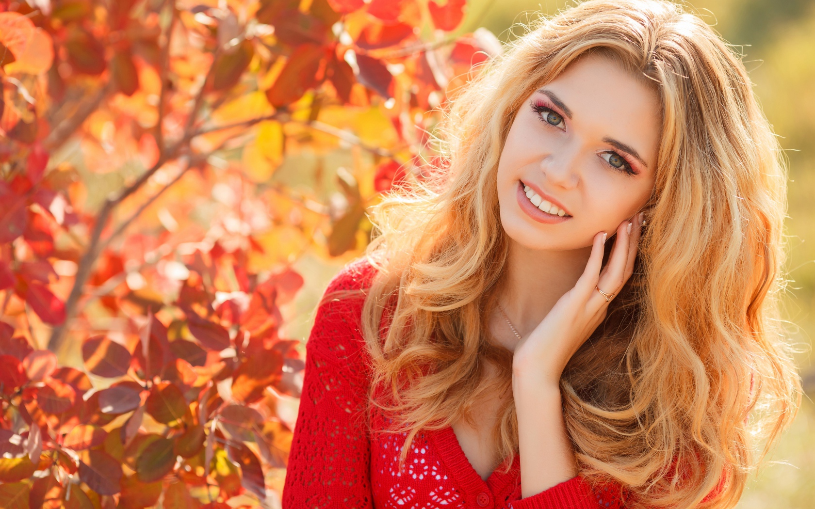 Красивая блондинка в красной кофте на улице осенью 