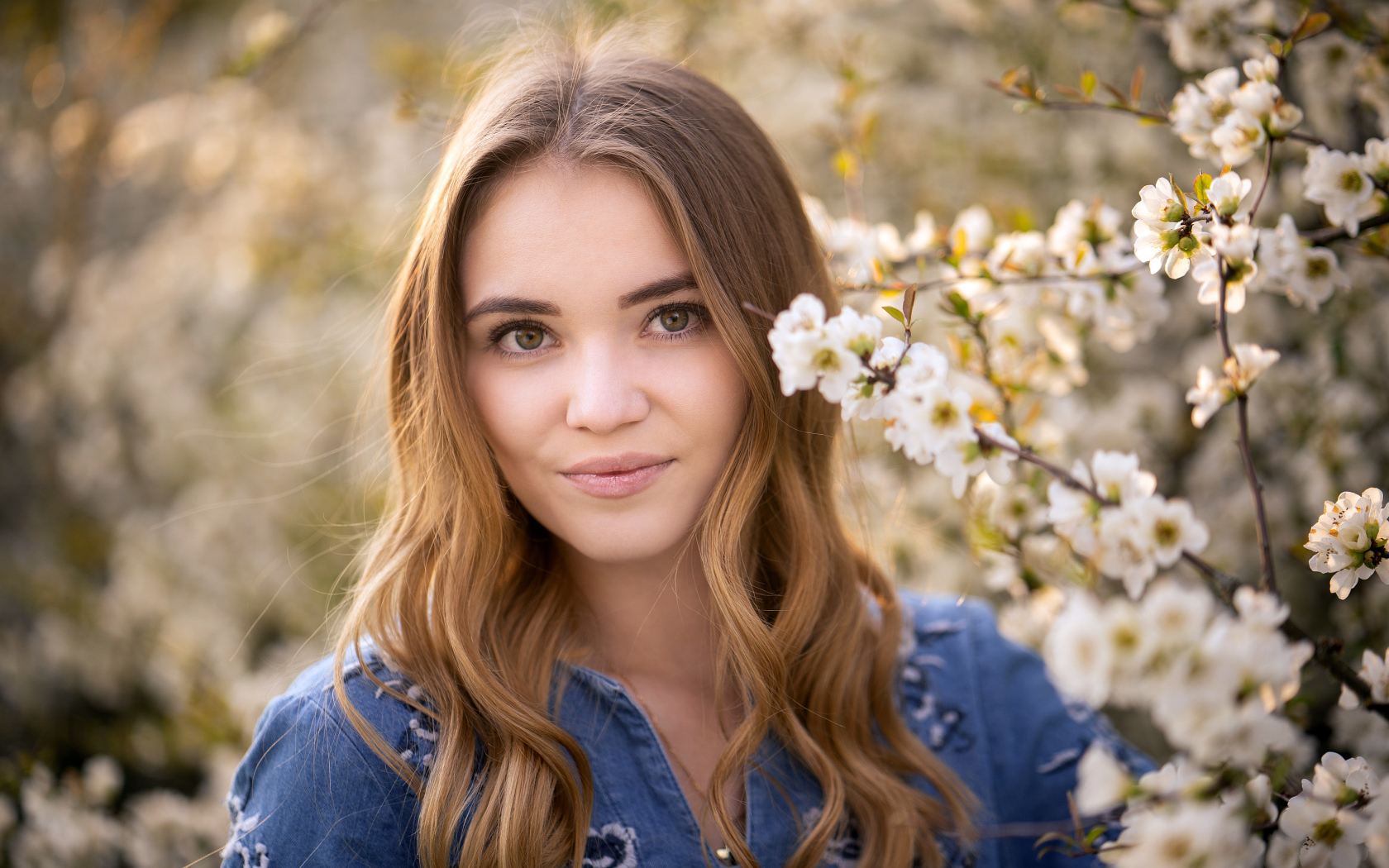 Красивая девушка у ветки с белыми цветами