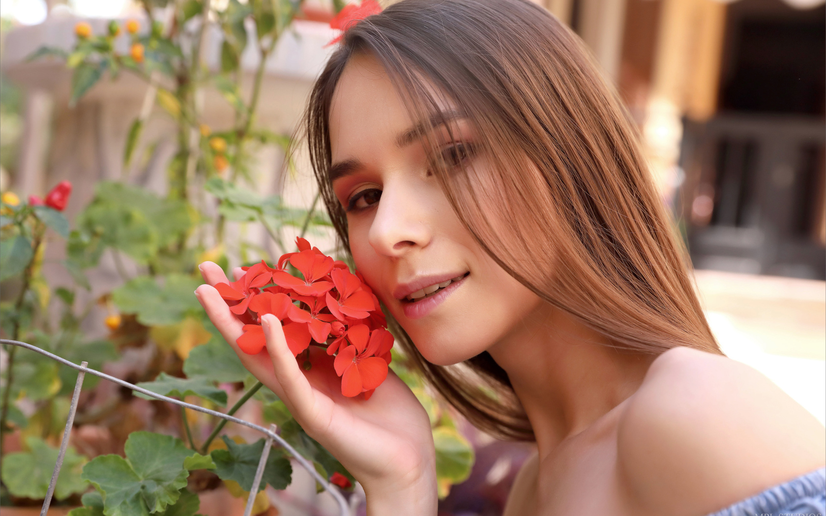 Красивая девушка с красным цветком герани 